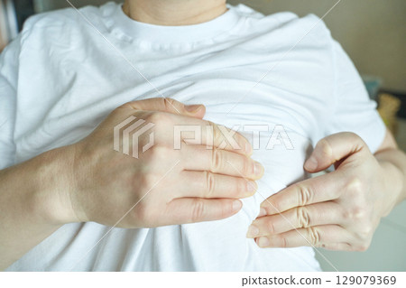 Close up of person in white shirt adjusting fabric with hands 129079369