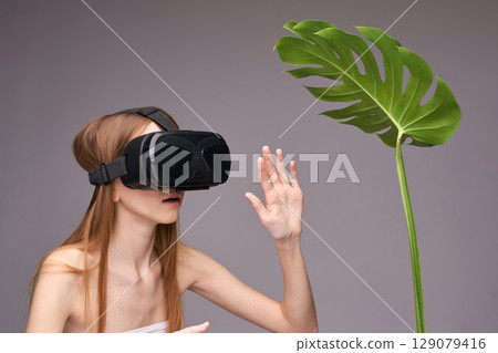 Young caucasian female using virtual reality headset interacting with plant 129079416