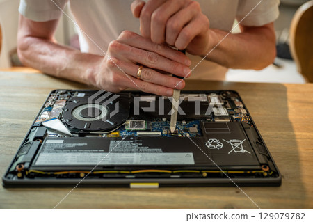 Man repairing laptop with tools on table, computer maintenance concept 129079782