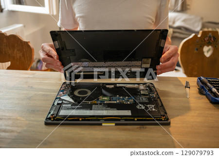 Man repairing laptop with tools on table, computer maintenance concept Man repairing laptop with tools on table, computer maintenance concept 129079793
