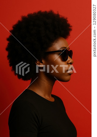 Stylish portrait of woman with afro and sunglasses on bold red background 129080327