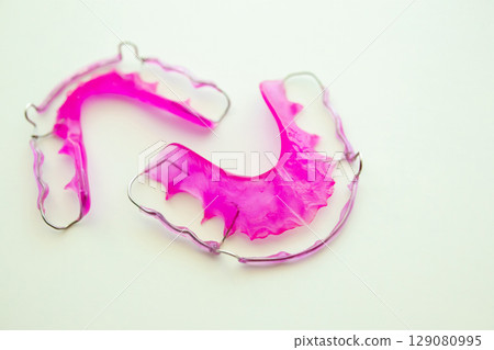Pink acrylic dental retainer on white background 129080995