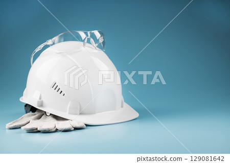 White construction worker safety helmet with personal protective equipment on blue background White construction worker safety helmet with personal protective equipment on blue background 129081642