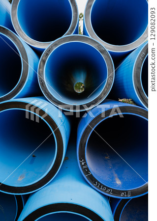 Blue PVC pipes stacked in a circular arrangement showcasing industrial materials and textures Blue PVC pipes stacked in a circular arrangement showcasing industrial materials and textures 129082093