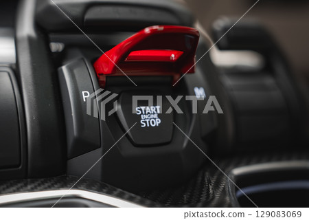 Detailed view of the Lamborghini Urus center console showing the red flip cover over the Start Engine Stop button, carbon fiber, and gear buttons. 129083069