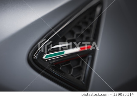 Detailed view of a Lamborghini Urus air vent featuring a black honeycomb grille, Italian flag emblem, and matte gray surface highlighting craftsmanship. Detailed view of a Lamborghini Urus air vent featuring a black honeycomb grille, Italian flag emblem, and matte gray surface highlighting craftsmanship. 129083114