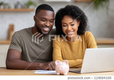 Happy couple planning budget using laptop and piggy bank at home Happy couple planning budget using laptop and piggy bank at home 129084100
