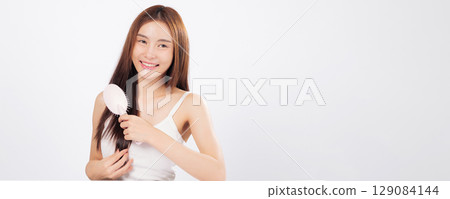 Hair management and radiant hair are central in this portrait as a woman combs gently, ideal for promoting healthy hair and salon-quality care at home. isolated studio white background Hair management and radiant hair are central in this portrait as a woman combs gently, ideal for promoting healthy hair and salon-quality care at home. isolated studio white background 129084144