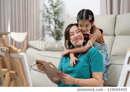 Joyful connection. Mother and daughter sharing a warm embrace during art time. 129084408