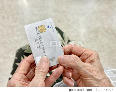 一位老人雙手的手指拿著信用卡_右邊的空間 129085092