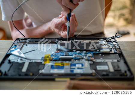 Man repairing laptop with tools on table, computer maintenance concept Man repairing laptop with tools on table, computer maintenance concept 129085196