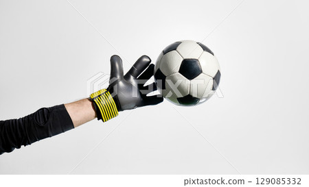 Goalkeeper reaching toward flying soccer ball in mid-air 129085332