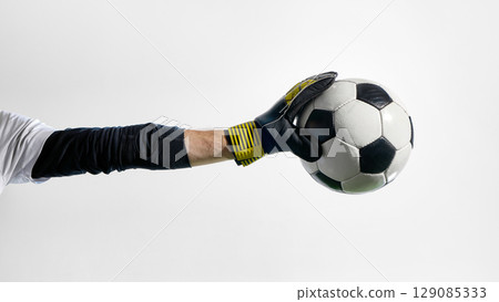 Goalkeeper holding soccer ball in gloved hand with extended arm 129085333