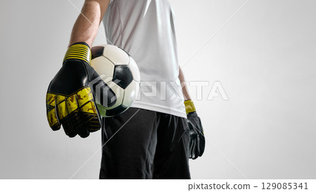 Soccer goalkeeper in gloves holding football close to camera 129085341