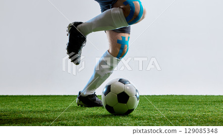 Soccer player with tape on knee getting ready to hit the ball on field 129085348