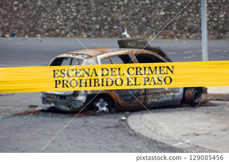 Mexican police tape in front of a burnt car Mexican police tape in front of a burnt car 129085456