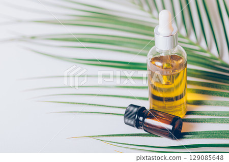 Bottle of essential oil is on a table next to a leaf Bottle of essential oil is on a table next to a leaf 129085648