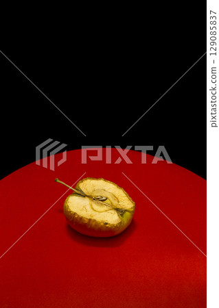 Old apple in a cut on a red-black background Old apple in a cut on a red-black background 129085837