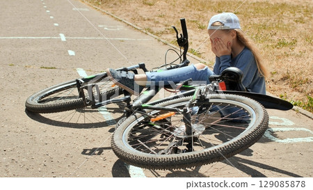 Schoolgirl weeping after bicycle accident on sunlit playground, showing emotional distress Schoolgirl weeping after bicycle accident on sunlit playground, showing emotional distress 129085878