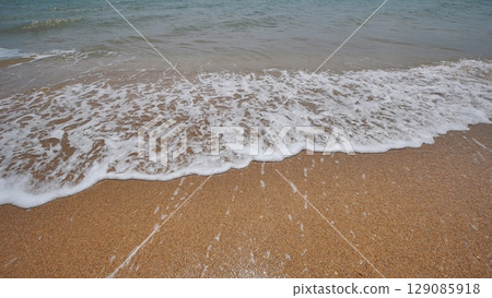 Gentle waves washing over golden sand on a sunny beach in crimea, creating a serene and peaceful atmosphere Gentle waves washing over golden sand on a sunny beach in crimea, creating a serene and peaceful atmosphere 129085918