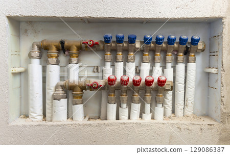 Pipes and valves for hot and cold water in heating and water supply system in boiler room closeup 129086387