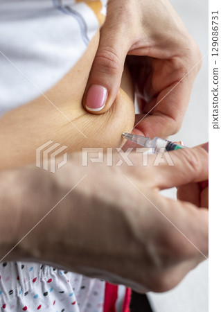 Close up shot of the woman with beautiful hands, preparing hormone medicine and injecting herself to the abdomen with pierced bellybutton. 129086731