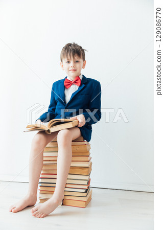 Boy sitting on stacks of educational books 129086770
