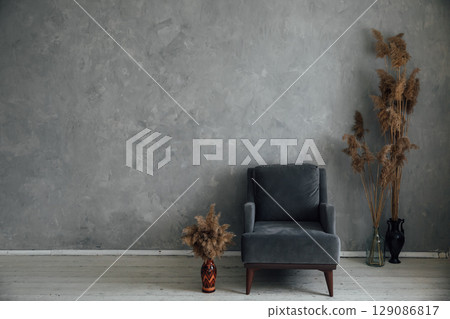 armchair and dried flowers in the interior of a gray room armchair and dried flowers in the interior of a gray room 129086817
