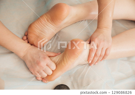 Masseur doing medical foot massage to woman Masseur doing medical foot massage to woman 129086826