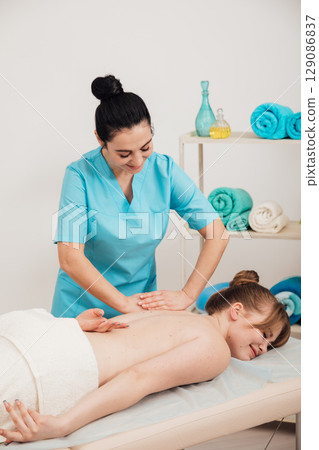 Masseur doing hands medical back massage to woman Masseur doing hands medical back massage to woman 129086837