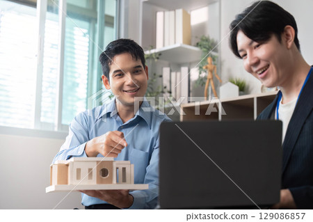 Architectural Collaboration. Professionals discussing building model and design concepts. 129086857