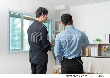 Client Consultation. Real estate agents discussing property options in modern office. 129086860