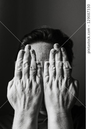 Woman Covering Face with Hands in Close-Up Portrait 129087330