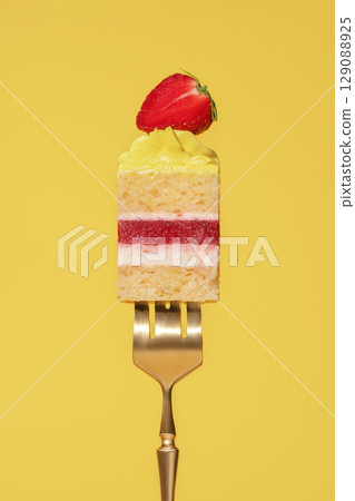 Colorful lemon and strawberry bento cake slice with layers of cream, fruit, and sponge on a golden fork against a vibrant yellow background, showcasing a delightful dessert concept Colorful lemon and strawberry bento cake slice with layers of cream, fruit, and sponge on a golden fork against a vibrant yellow background, showcasing a delightful dessert concept 129088925