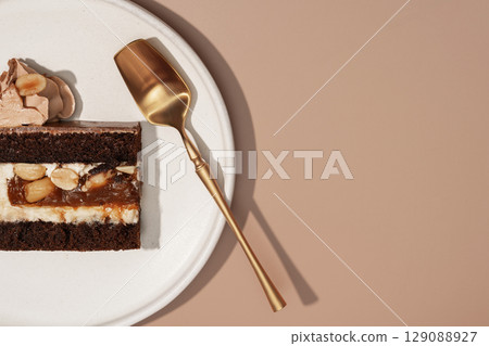 Bento cake slice on a white plate with a golden serving spoon, showcasing rich layers of chocolate, cream, and nuts, emphasizing the delightful cross-section of this dessert concept Bento cake slice on a white plate with a golden serving spoon, showcasing rich layers of chocolate, cream, and nuts, emphasizing the delightful cross-section of this dessert concept 129088927