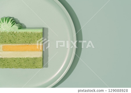 Colorful bento cake slice displayed on a plate, showcasing layers of green pistachio, cream, mango, and passion fruit, highlighting the artistic cross-section of this delightful dessert concept Colorful bento cake slice displayed on a plate, showcasing layers of green pistachio, cream, mango, and passion fruit, highlighting the artistic cross-section of this delightful dessert concept 129088928