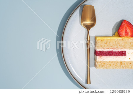 Bento cake slice on a plate with a golden spoon, showcasing vibrant layers of cream, fruit, and sponge, highlighting the intricate cross-section and inviting dessert presentation concept Bento cake slice on a plate with a golden spoon, showcasing vibrant layers of cream, fruit, and sponge, highlighting the intricate cross-section and inviting dessert presentation concept 129088929