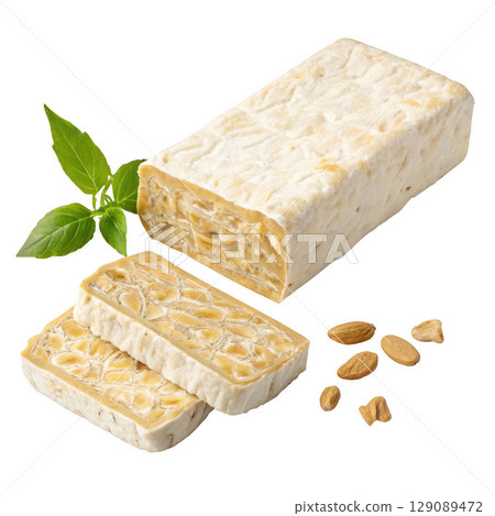 block of raw tempeh with firm texture is displayed alongside sliced pieces, soybeans, and green leaf, emphasizing its natural and healthy appeal 129089472