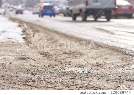Busy urban street in winter with snow, cars, and slush on the roadside Busy urban street in winter with snow, cars, and slush on the roadside 129089744