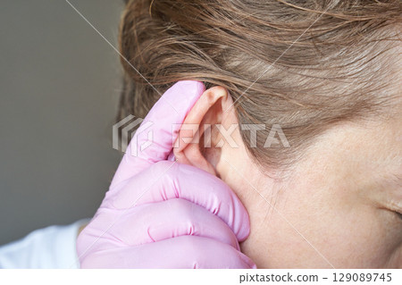 close up of female adult with caucasian skin having ear examined by doctor 129089745