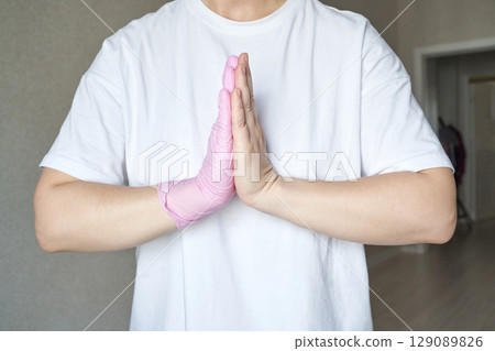 Caucasian male adult wearing pink glove and white t shirt with hands in prayer Caucasian male adult wearing pink glove and white t shirt with hands in prayer 129089826