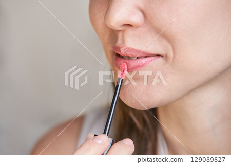 Young caucasian female applying pink lipstick closeup Young caucasian female applying pink lipstick closeup 129089827