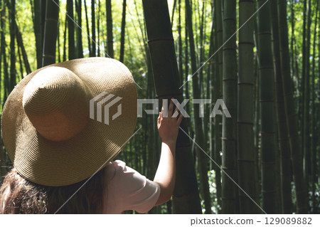 Girl in Straw Hat Exploring Bamboo Forest in Asia Girl in Straw Hat Exploring Bamboo Forest in Asia 129089882