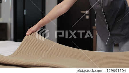 Woman housekeeper preparing bed clothes in the hotel room. Cleaning service in hotel rooms, hotel business. Woman housekeeper preparing bed clothes in the hotel room. Cleaning service in hotel rooms, hotel business. 129091504