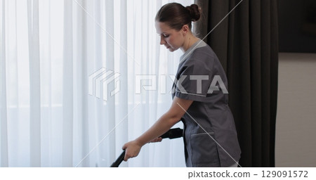 Housemaid cleaning carpet in hotel room with vacuum cleaner In hotel room. Hotel service. Housemaid cleaning carpet in hotel room with vacuum cleaner In hotel room. Hotel service. 129091572