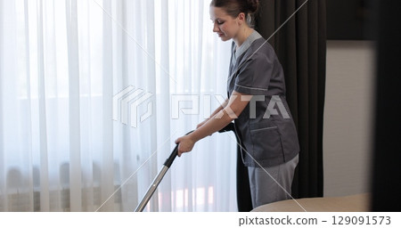 Professional housekeeper woman hovering floor in bedroom apartment in hotel while serving room. Hotel service. Professional housekeeper woman hovering floor in bedroom apartment in hotel while serving room. Hotel service. 129091573