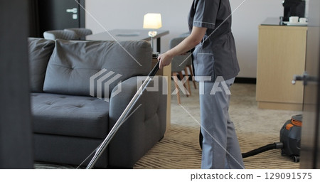 Housemaid cleaning carpet in hotel room with vacuum cleaner In hotel room. Hotel service. Housemaid cleaning carpet in hotel room with vacuum cleaner In hotel room. Hotel service. 129091575