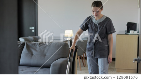 Professional housekeeper woman hovering floor in bedroom apartment in hotel while serving room. Hotel service. Professional housekeeper woman hovering floor in bedroom apartment in hotel while serving room. Hotel service. 129091576