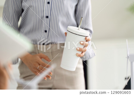 Sustainability in Action: Professional discussing eco-friendly practices with reusable cup 129091603