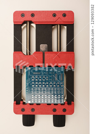 Universal professional holder for circuit boards and microchips. Blue printed circuit board for soldering. 129093382